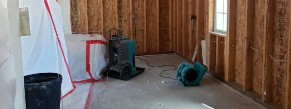 Water damage restoration in progress inside a Dunbar, WV home, showing exposed wall studs, drying equipment, and containment barriers for mold prevention.